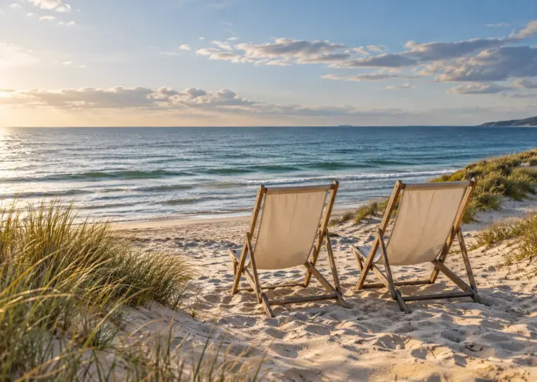 KI-Symbolbild: Zwei leere Strandstühle mit Blick auf das Meer